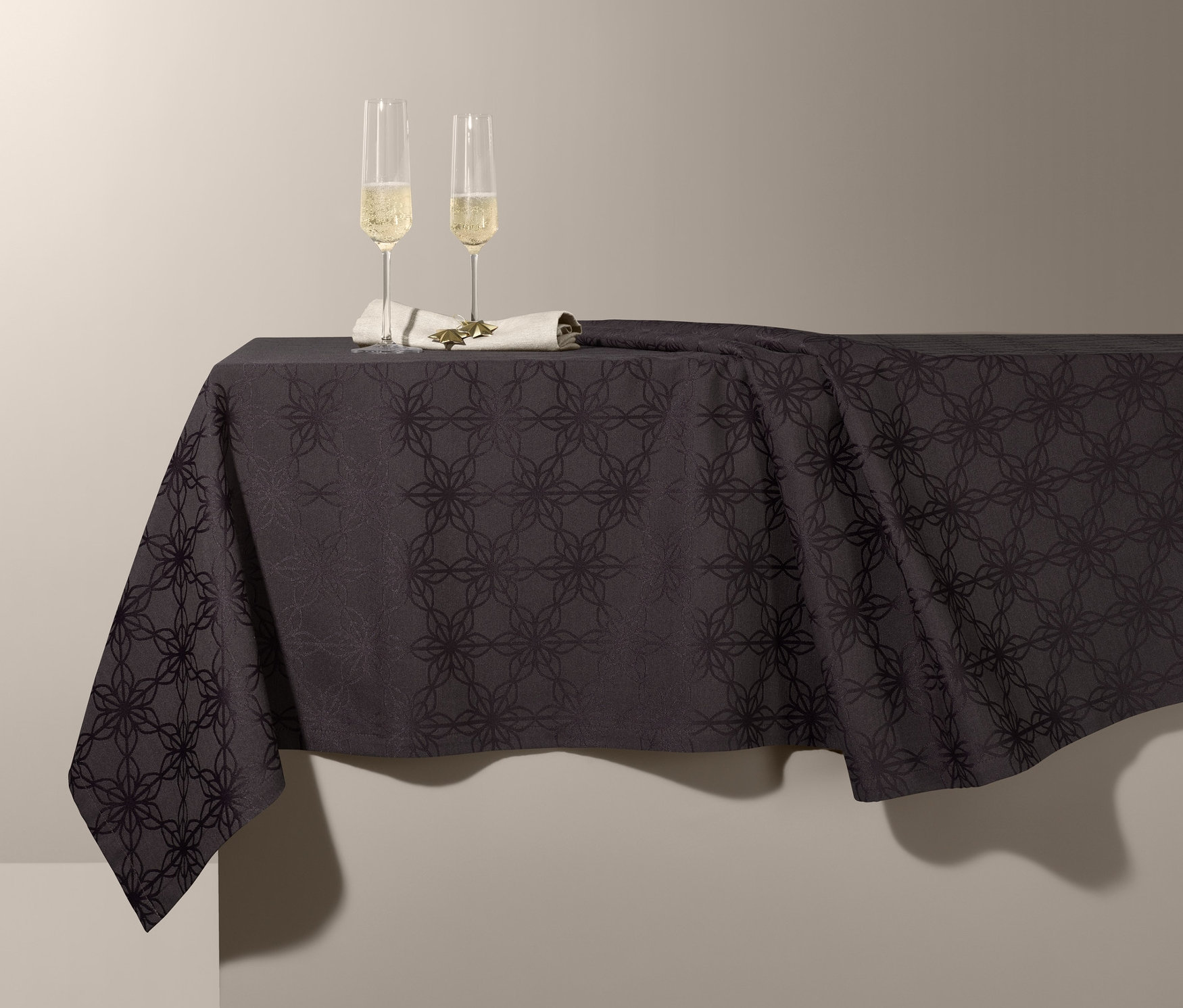 Dwa kieliszki do szampana na obrusie żakardowym.