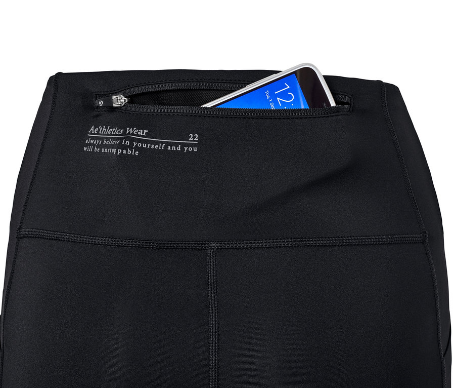 Zbliżenie na czarne, damskie profesjonalne spodnie do biegania z telefonem w kieszeni.
