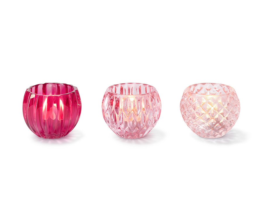 Trzy szklane świeczniki na świeczki typu tea light w różnych odcieniach różu.