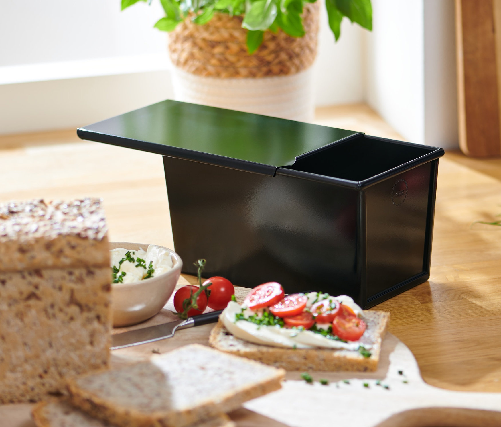 Chleb pełnoziarnisty i tostowy obok formy do pieczenia chleba.