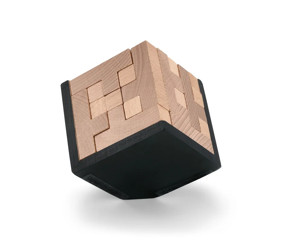 Zbliżenie na drewnianą kostkę Puzzle IQ z czarną podstawą.