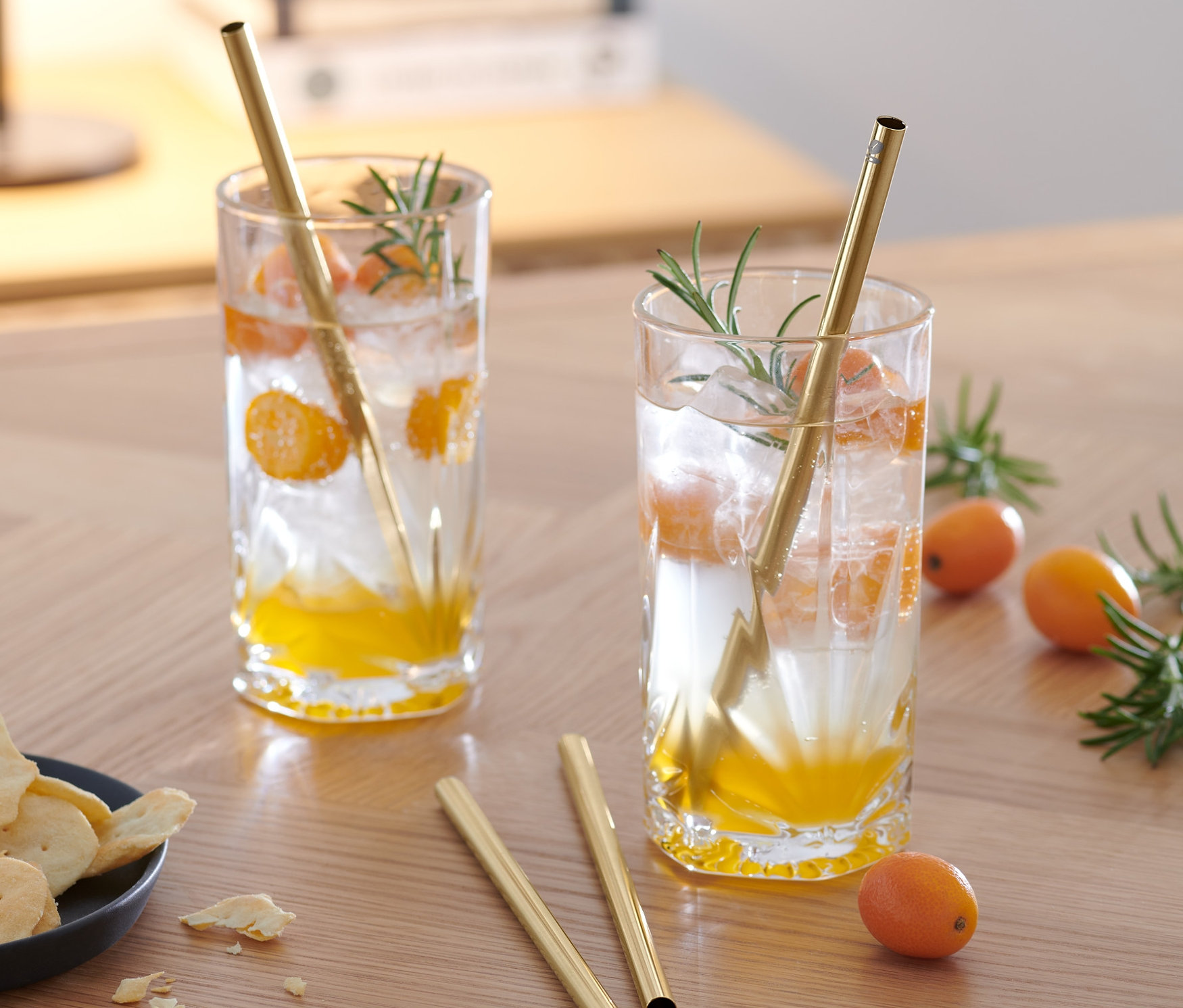 Dwa napoje z kawałkami owoców i metalowymi słomkami do picia, 4 sztuki, na drewnianym stole.
