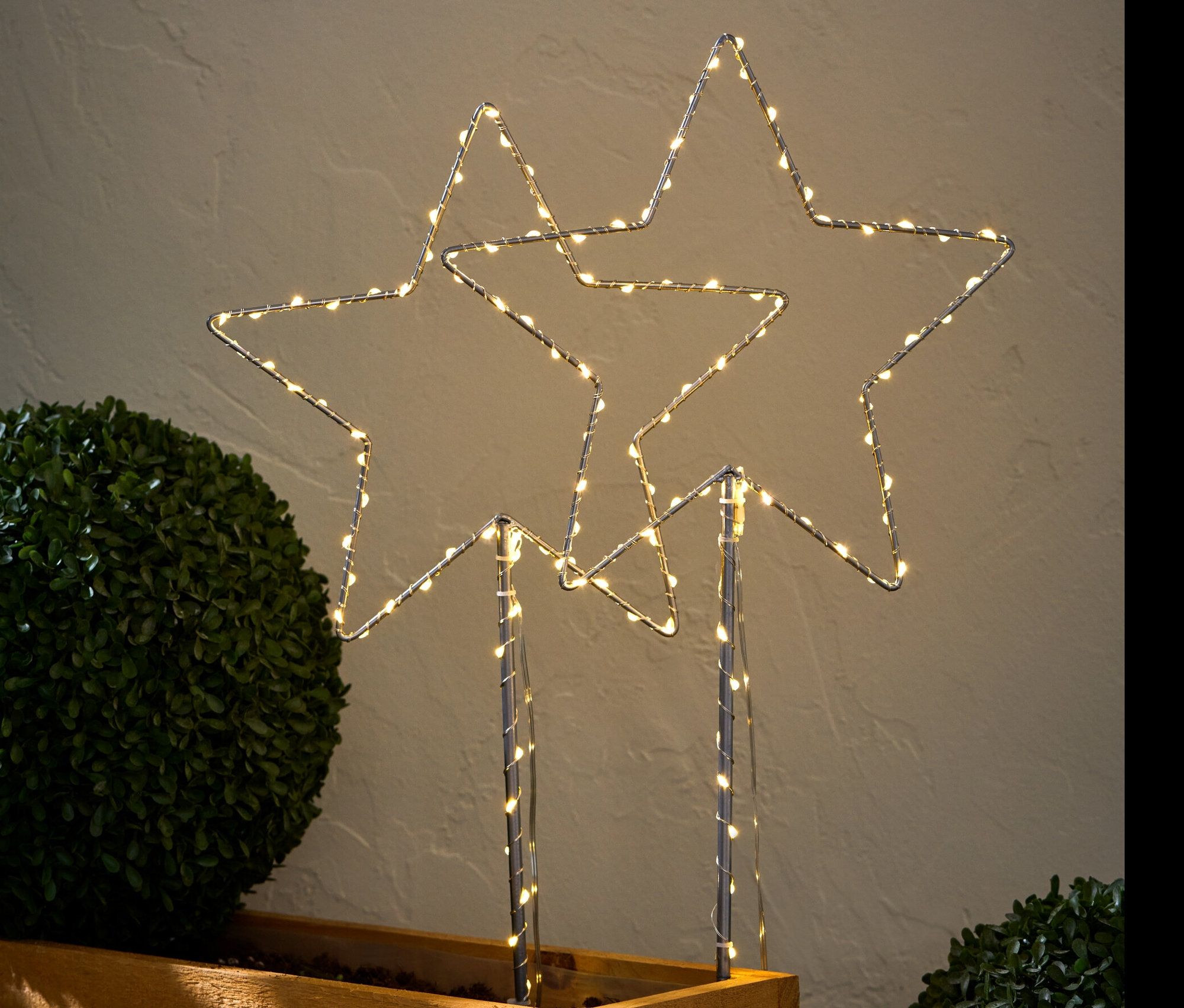 Dwa duże lampy LED do wbicia w ziemię „Gwiazda” w drewnianej donicy.