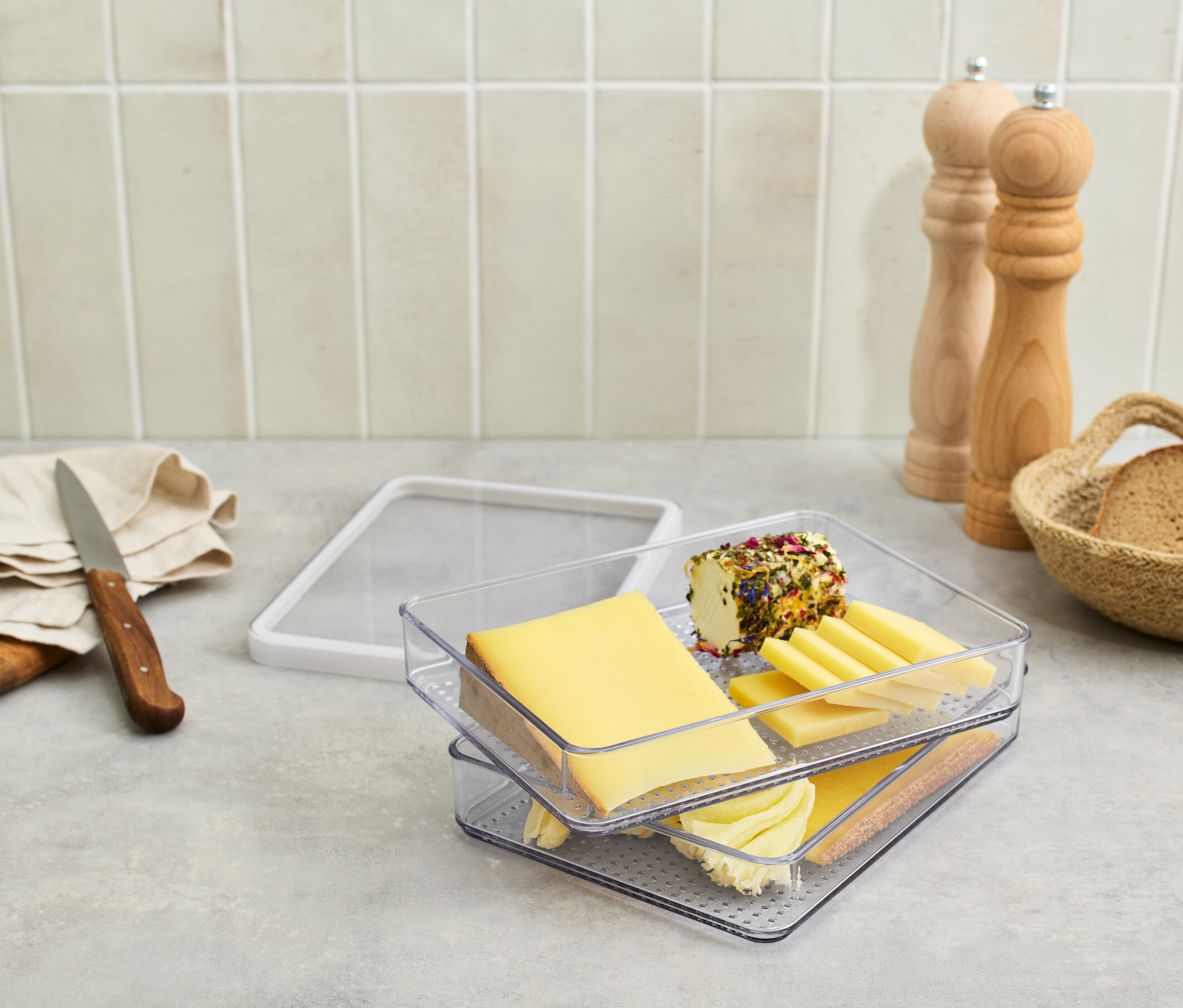 Pojemnik na wędliny i sery z serami i wędlinami na stole.