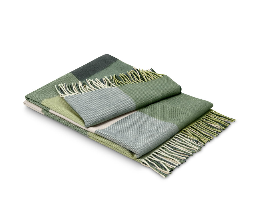 Złożony zielony koc w kratę z frędzlami.