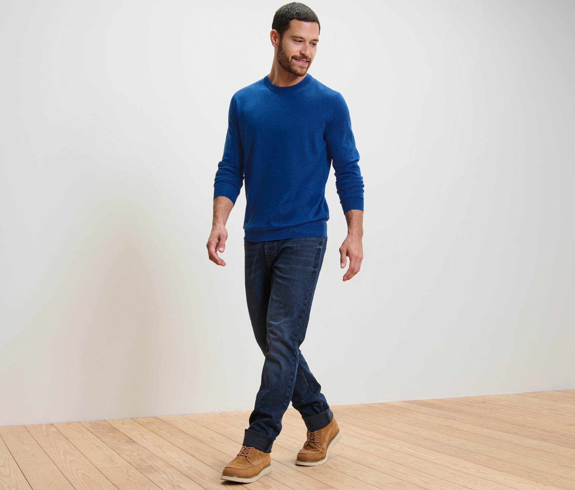 Mężczyzna idzie i ma na sobie niebieski sweter z wełny merino.
