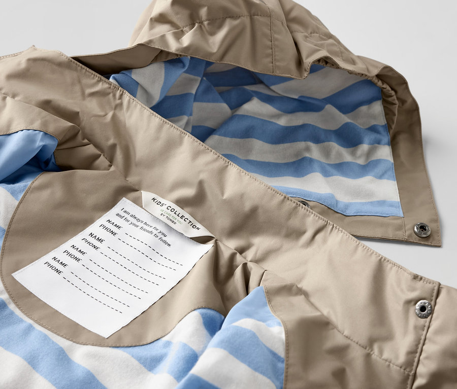 Zbliżenie na brązową kurtkę przeciwdeszczową dla dzieci z niebiesko-białą podszewką w paski.