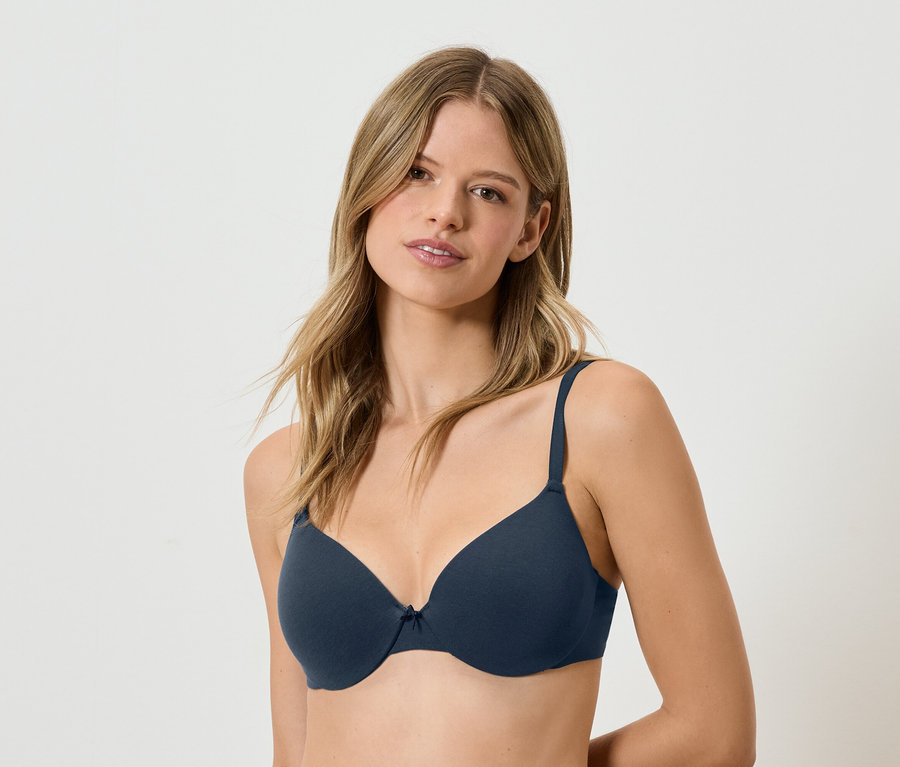 Kobieta z brązowymi włosami ma na sobie granatowy biustonosz.