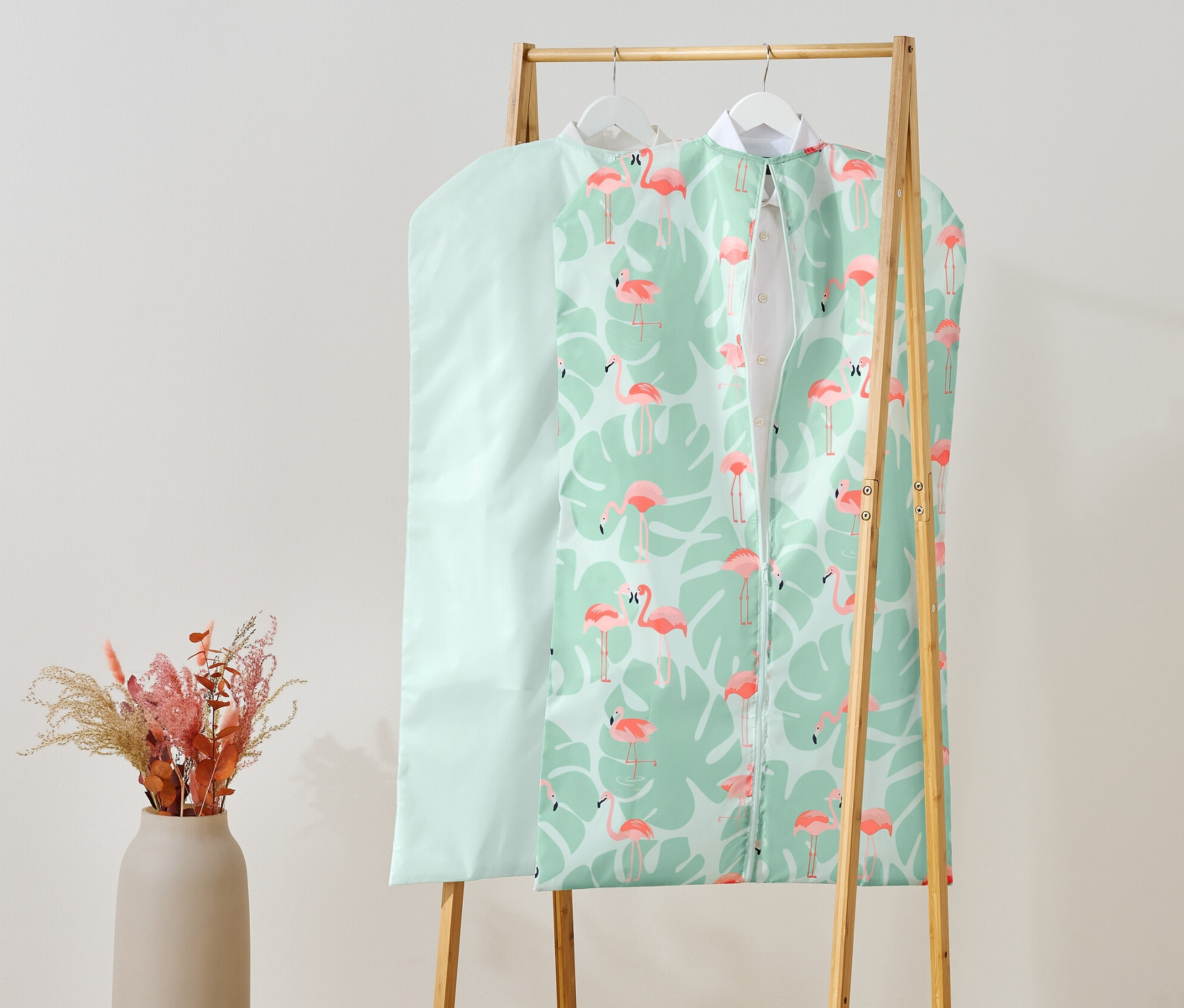 Dwa pokrowce na ubrania wiszą na drewnianym stojaku.