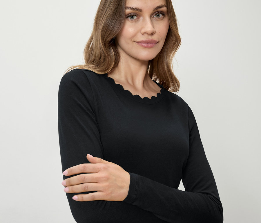 Kobieta ma na sobie czarną koszulkę z długim rękawem i ozdobnym brzegiem.