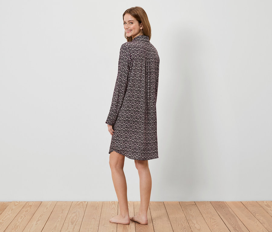 Kobieta w wzorzystej koszuli nocnej z długim rękawem spogląda przez ramię.