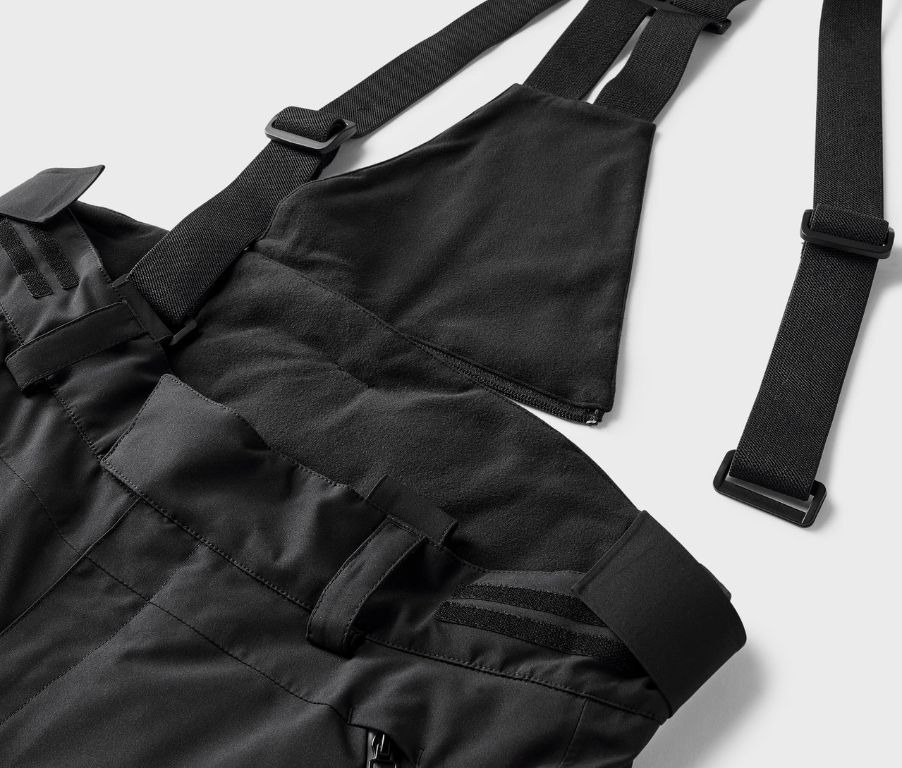 Czarne spodnie narciarskie z szelkami i regulowanymi paskami.