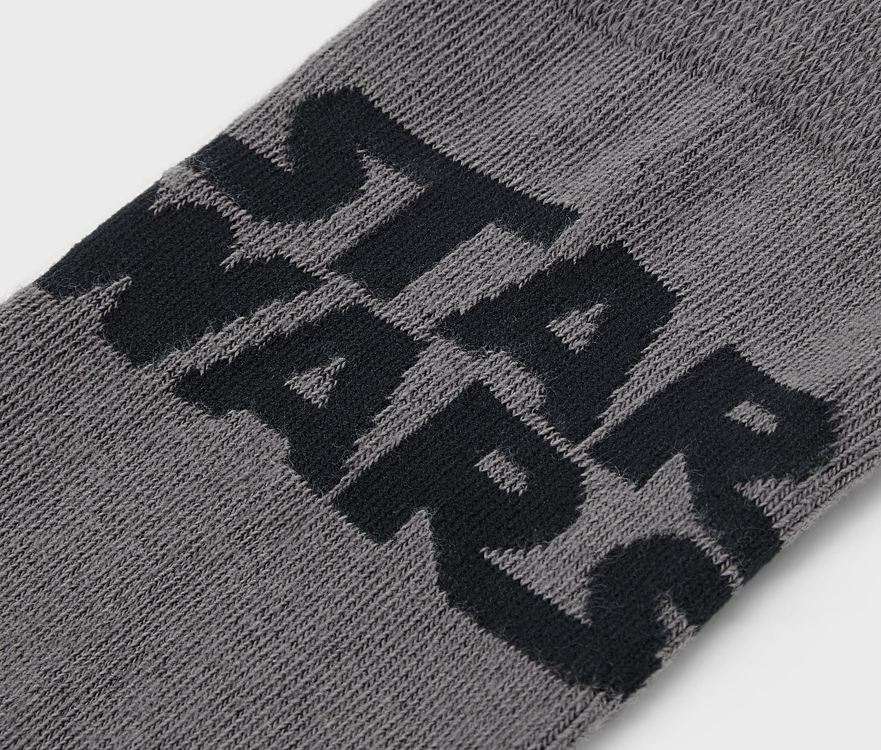 Zbliżenie na szarą skarpetę z czarnym napisem STAR WARS.