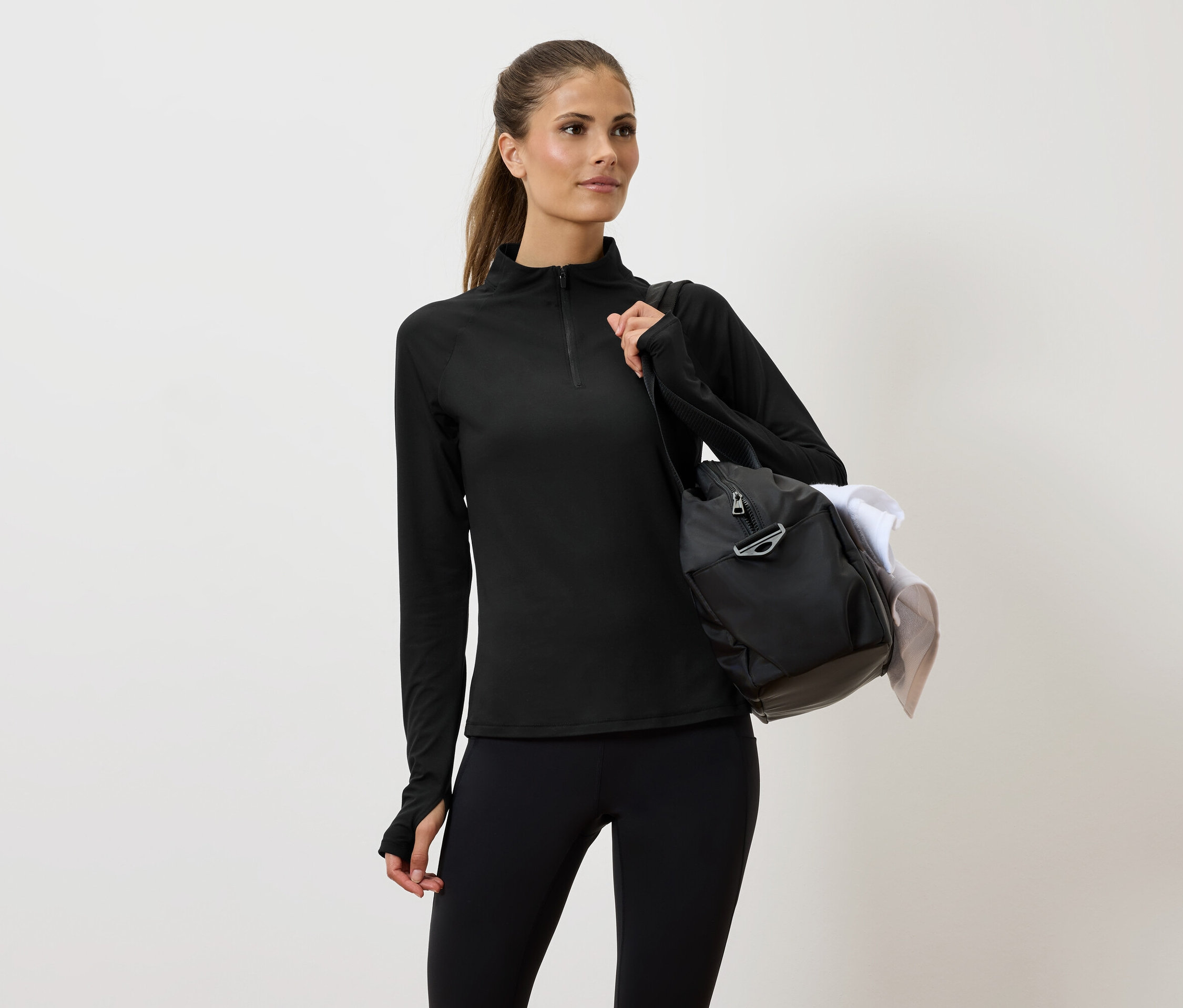 Kobieta w czarnym stroju sportowym z torbą na ramieniu.