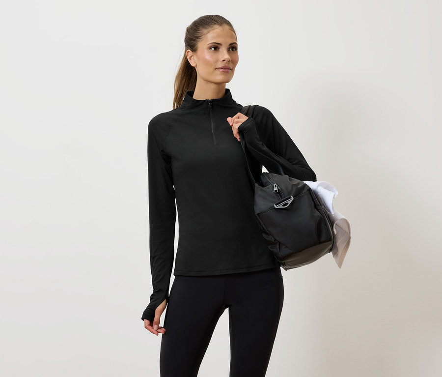 Kobieta w czarnym stroju sportowym z torbą na ramieniu.