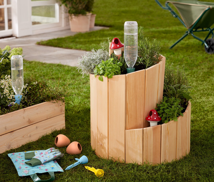 Na trawniku stoi drewniana grządka »Ślimak«, obsadzona ziołami i warzywami.