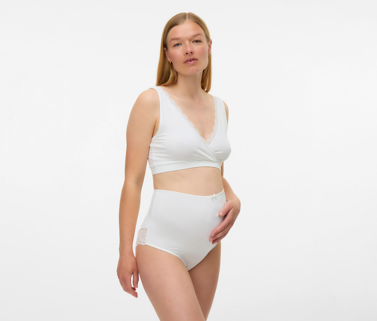 Kobieta ma na sobie biały biustonosz ciążowy MAMALICIOUS „MLHELENA”, 2 sztuki i majtki z koronką.