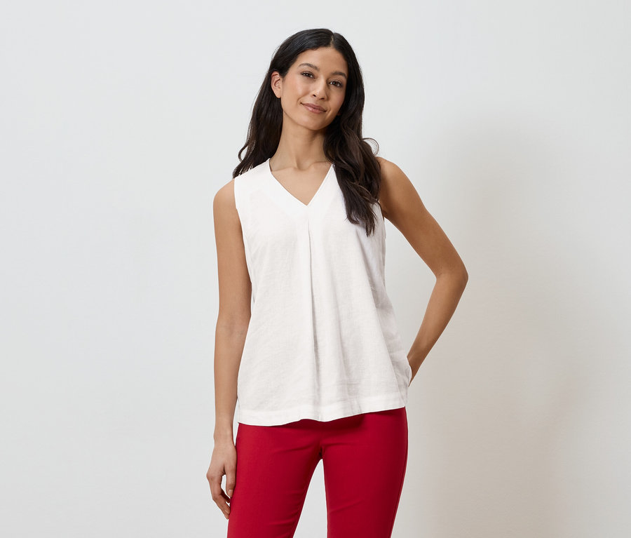 Kobieta ma na sobie białą bluzkę bez rękawów i czerwone spodnie.