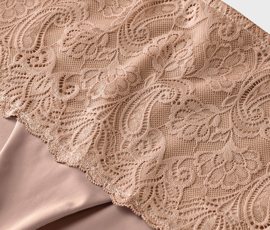 Bliska faktura beżowej koronki na beżowym materiale.