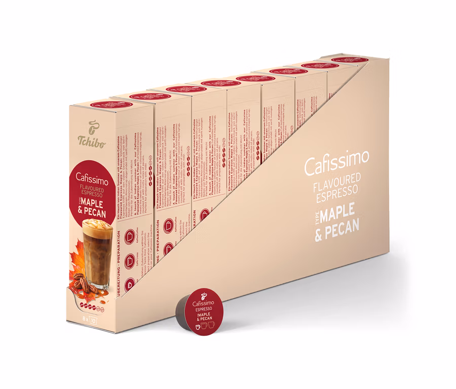 Beżowe pudełko ekspozycyjne zawiera 80 kapsułek kawy Cafissimo Flavoured Espresso - Maple & Pecan. Przednie opakowanie przedstawia napój kawowy z liśćmi klonu i orzechami pekan, a pojedyncza ciemnoczerwona kapsułka leży z przodu.