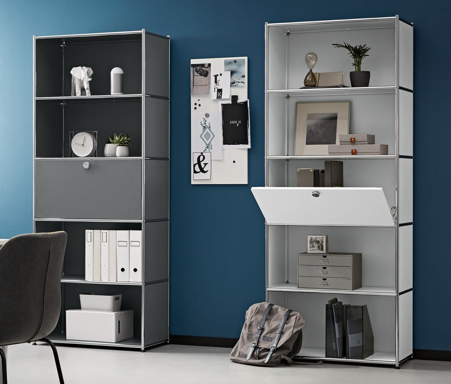 Pokój z biurkiem, krzesłem i dwoma wysokimi regałami metalowymi z półką zasłoniętą regulowaną klapą. Po lewej stronie metalowy kontener na kółkach, na stole laptop.