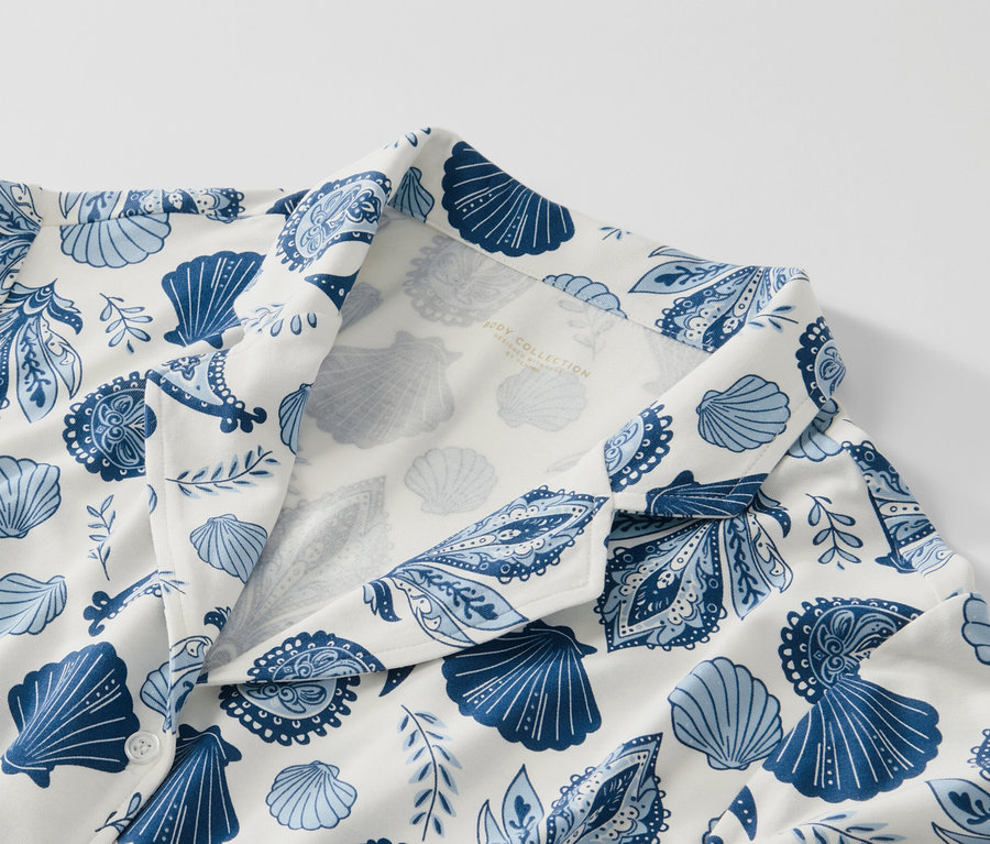 Zbliżenie piżamy z niebieskim wzorem muszelek i paisley na białym tle.