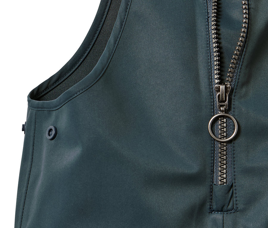 Szczegół spodni przeciwdeszczowych dla dzieci z zamkiem błyskawicznym i guzikiem.