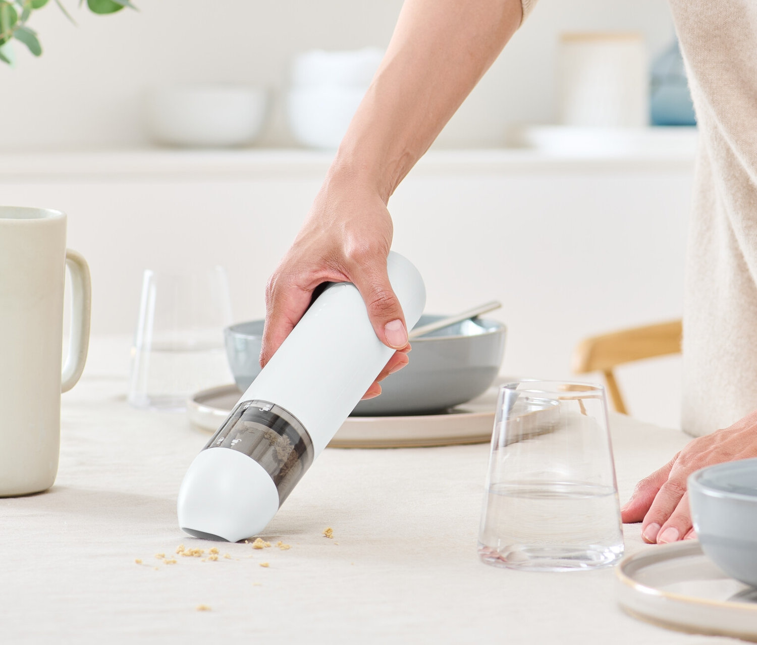 Kobieta używa bezprzewodowego odkurzacza ręcznego na stole.