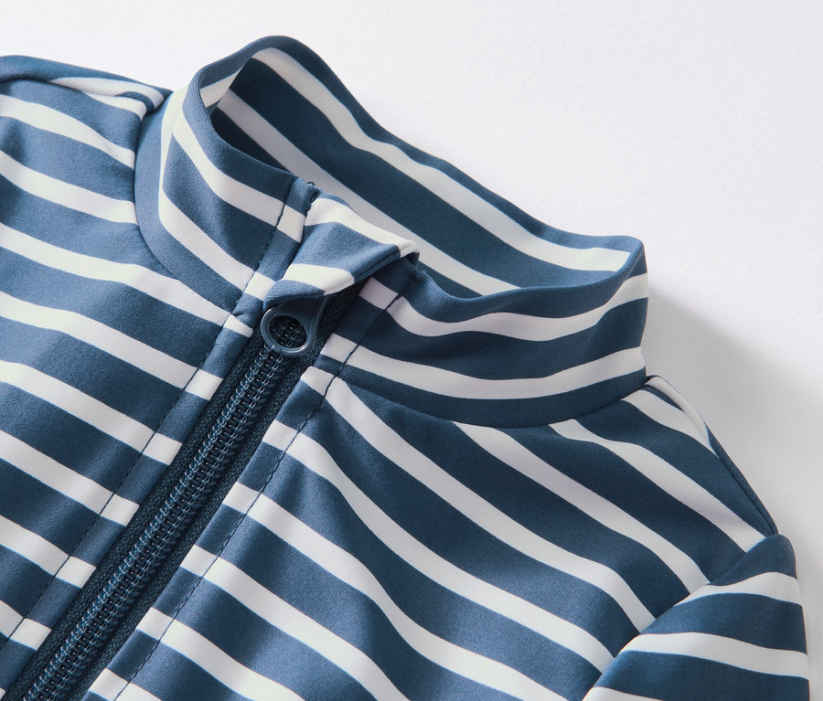 Zbliżenie na niebiesko-biały kombinezon niemowlęcy w paski z filtrem UV 80 i zamkiem błyskawicznym.