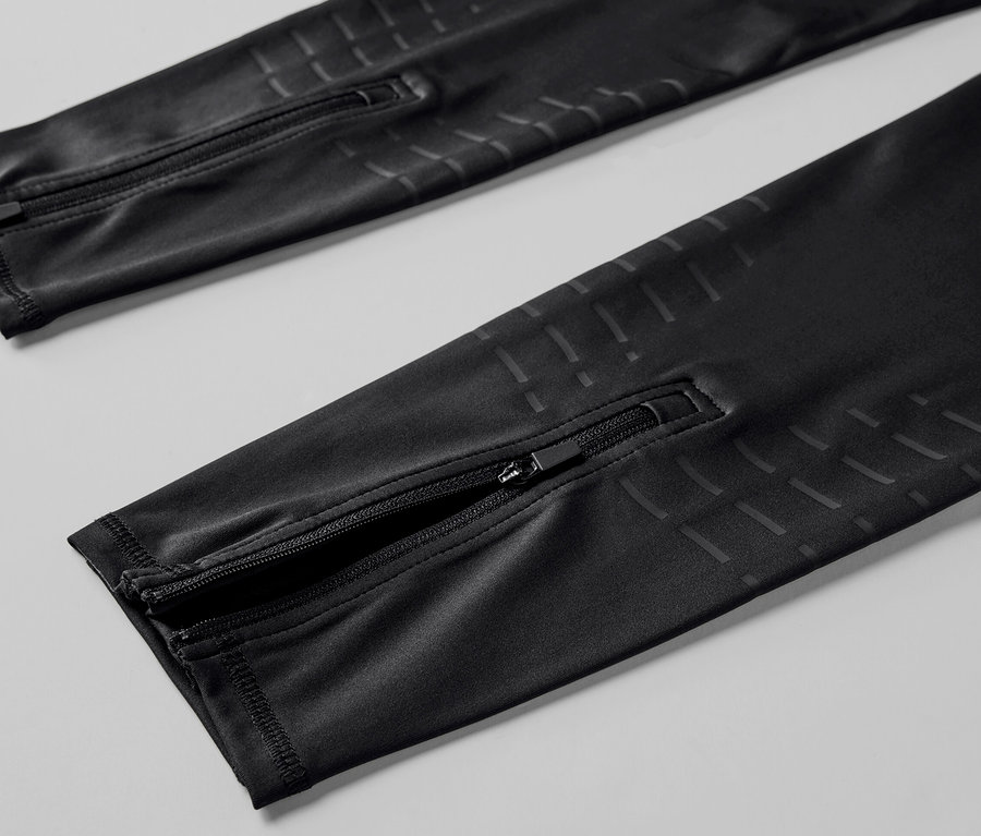 Szczegółowy widok czarnych legginsów do biegania z zamkami błyskawicznymi na nogawkach.