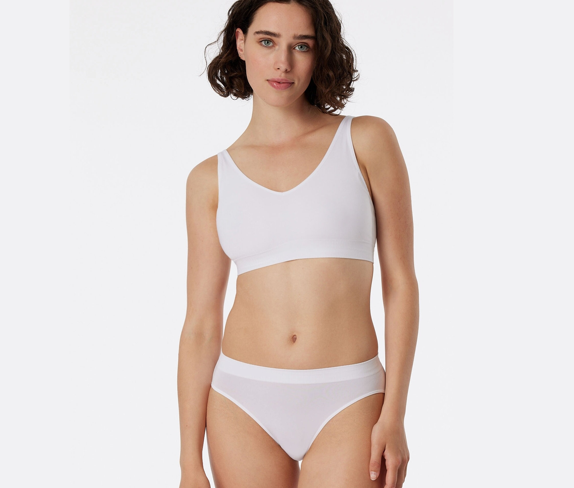 Kobieta ma na sobie biały biustonosz sportowy i białe figi SCHIESSER.