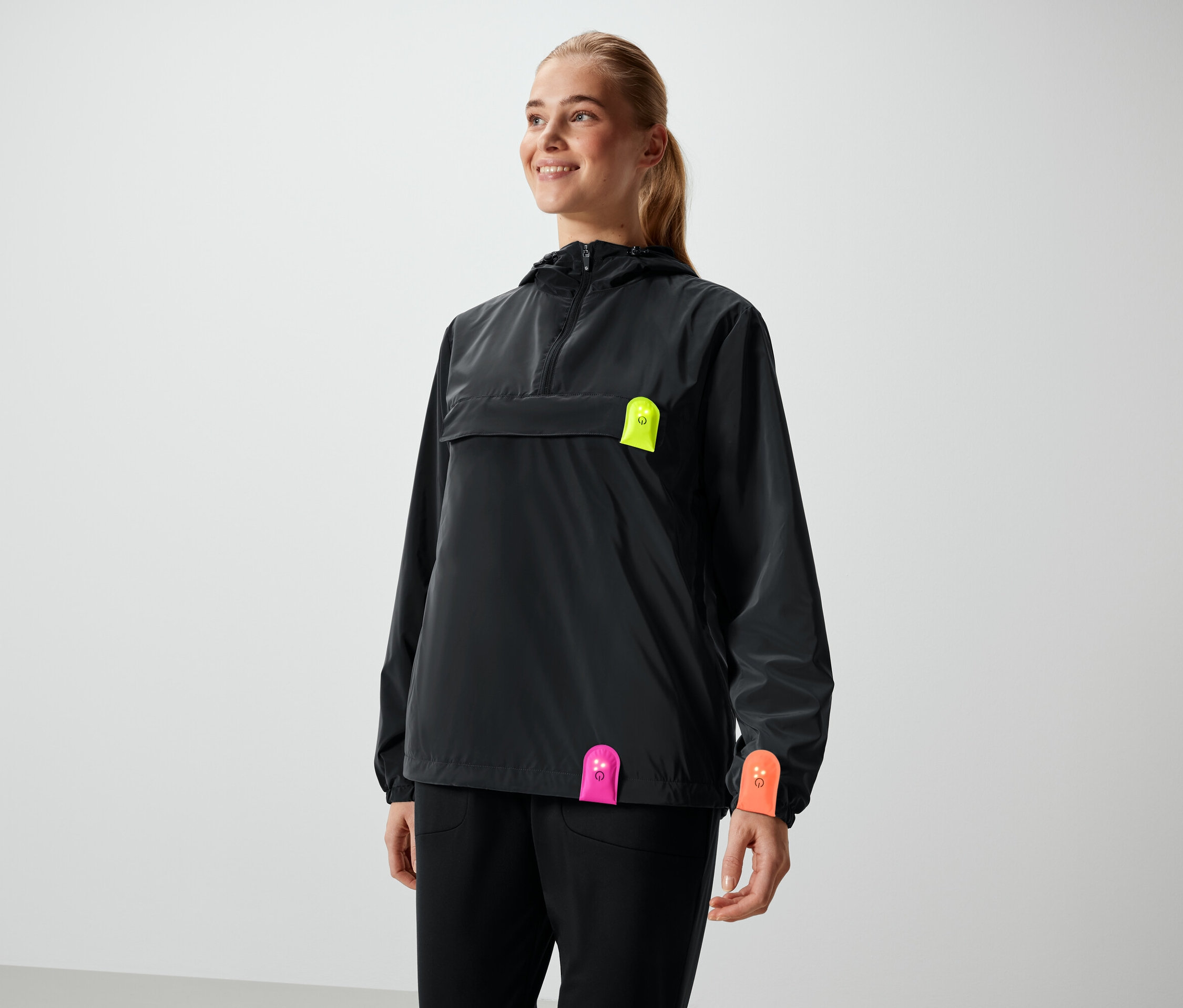 Uśmiechnięta kobieta w czarnej kurtce z neonowymi detalami.