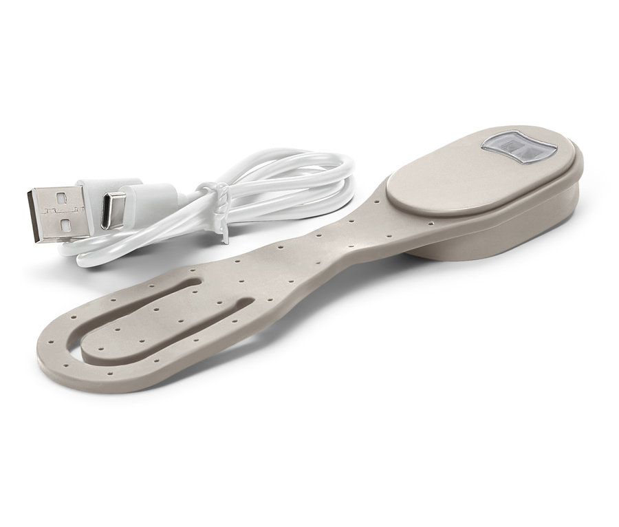 Beżowy klips do książek ze światłem i dołączonym kablem USB do ładowania leży na białym tle.