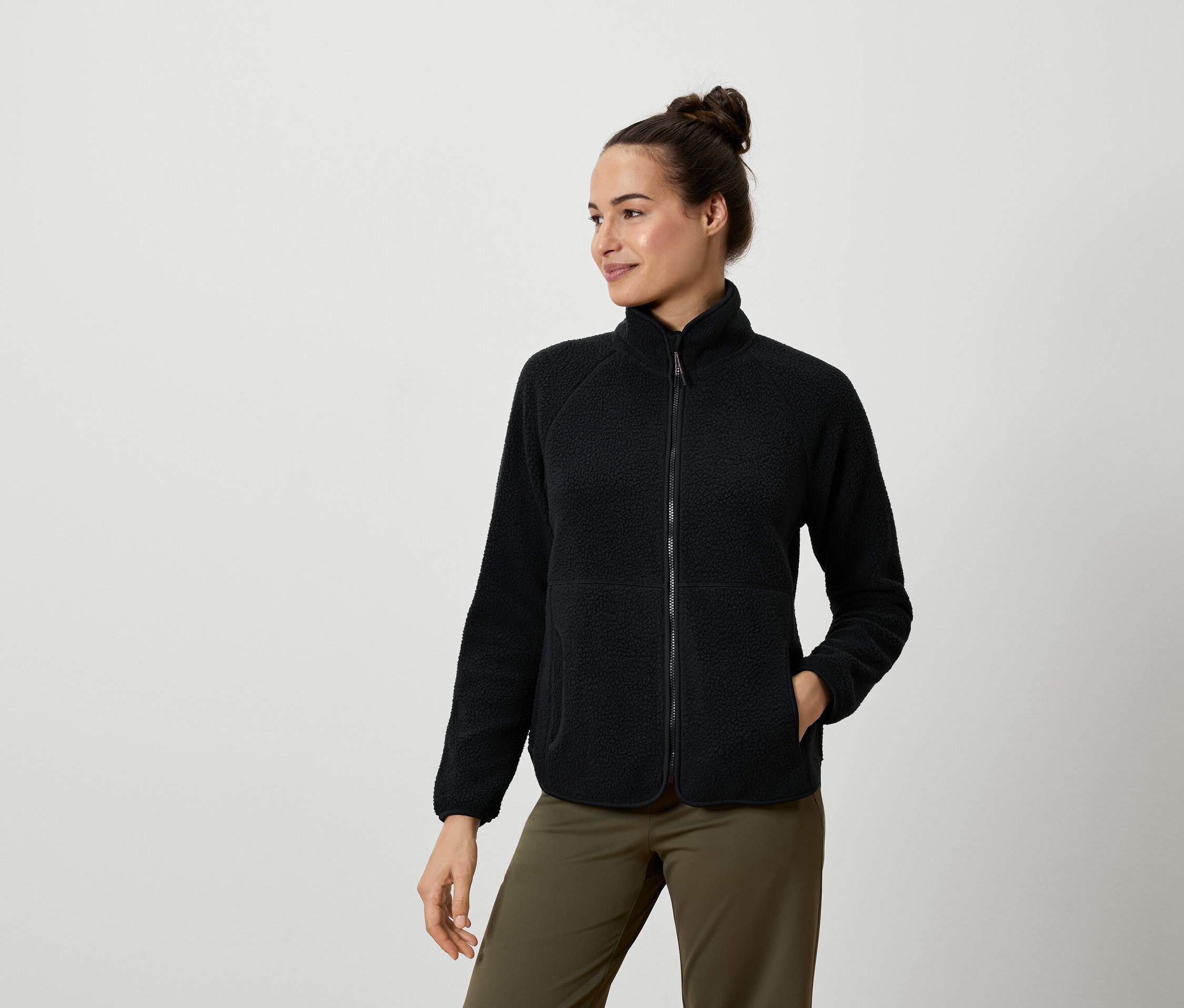 Kobieta ma na sobie czarną bluzę polarową i oliwkowozielone spodnie.