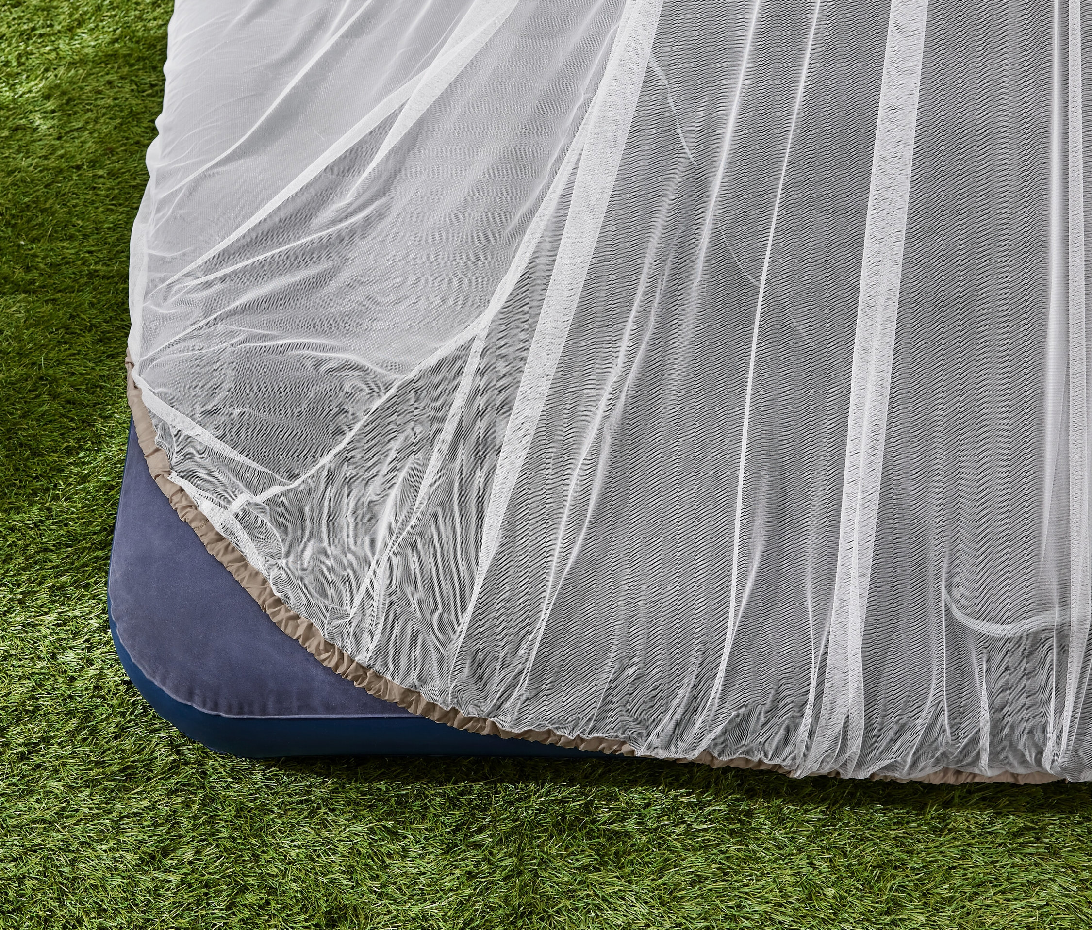 Moskitiera podróżna na materacu na trawie.