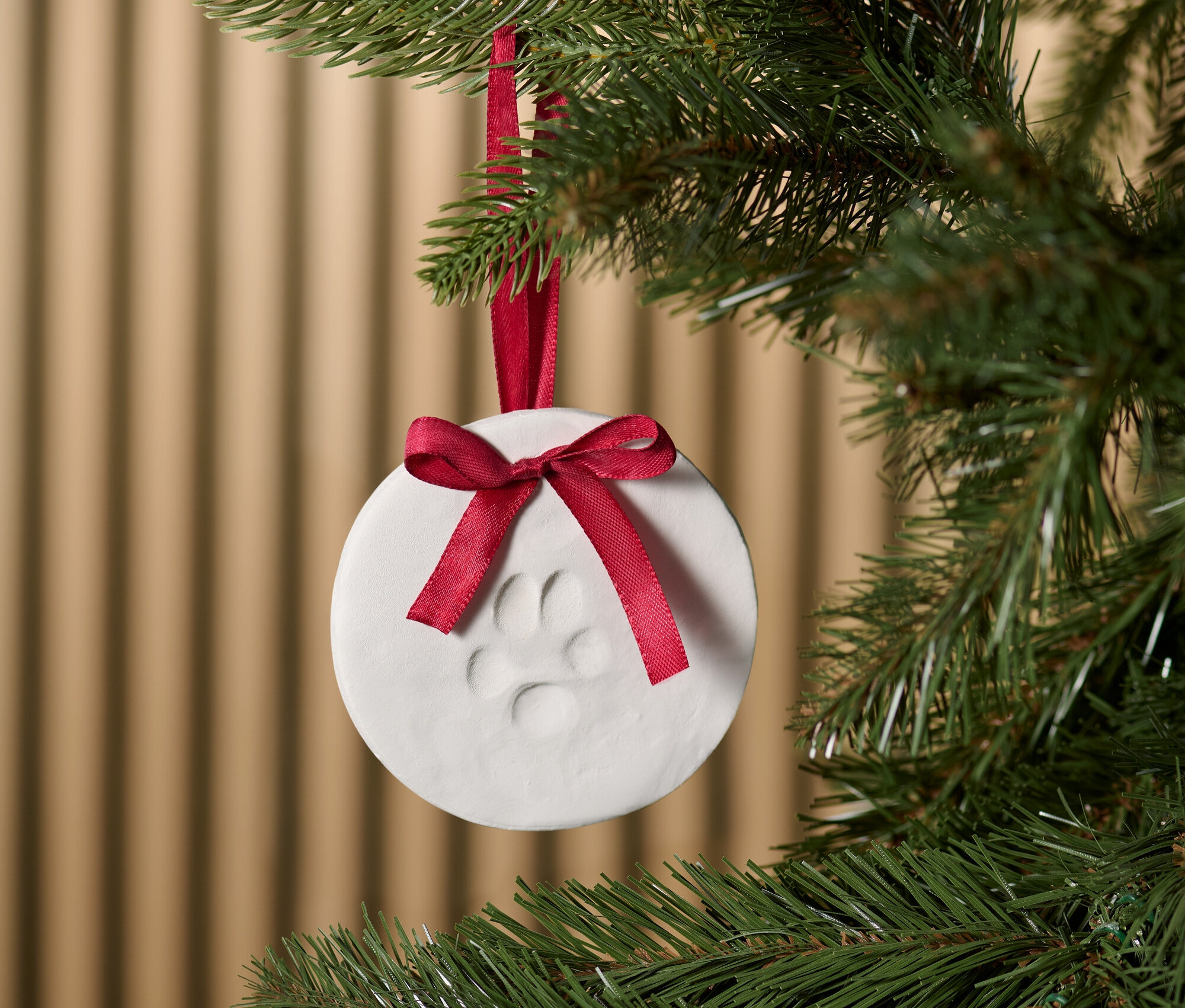 Na choince wisi biała ozdoba z odciskiem łapy i czerwoną wstążką.