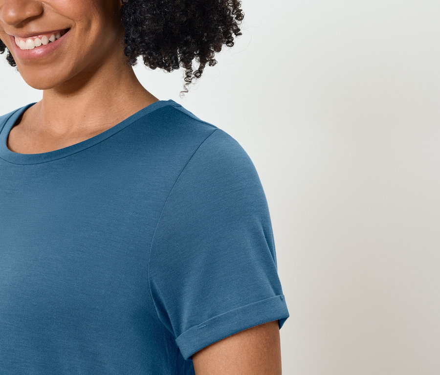 Uśmiechnięta kobieta ma na sobie niebieską koszulkę.