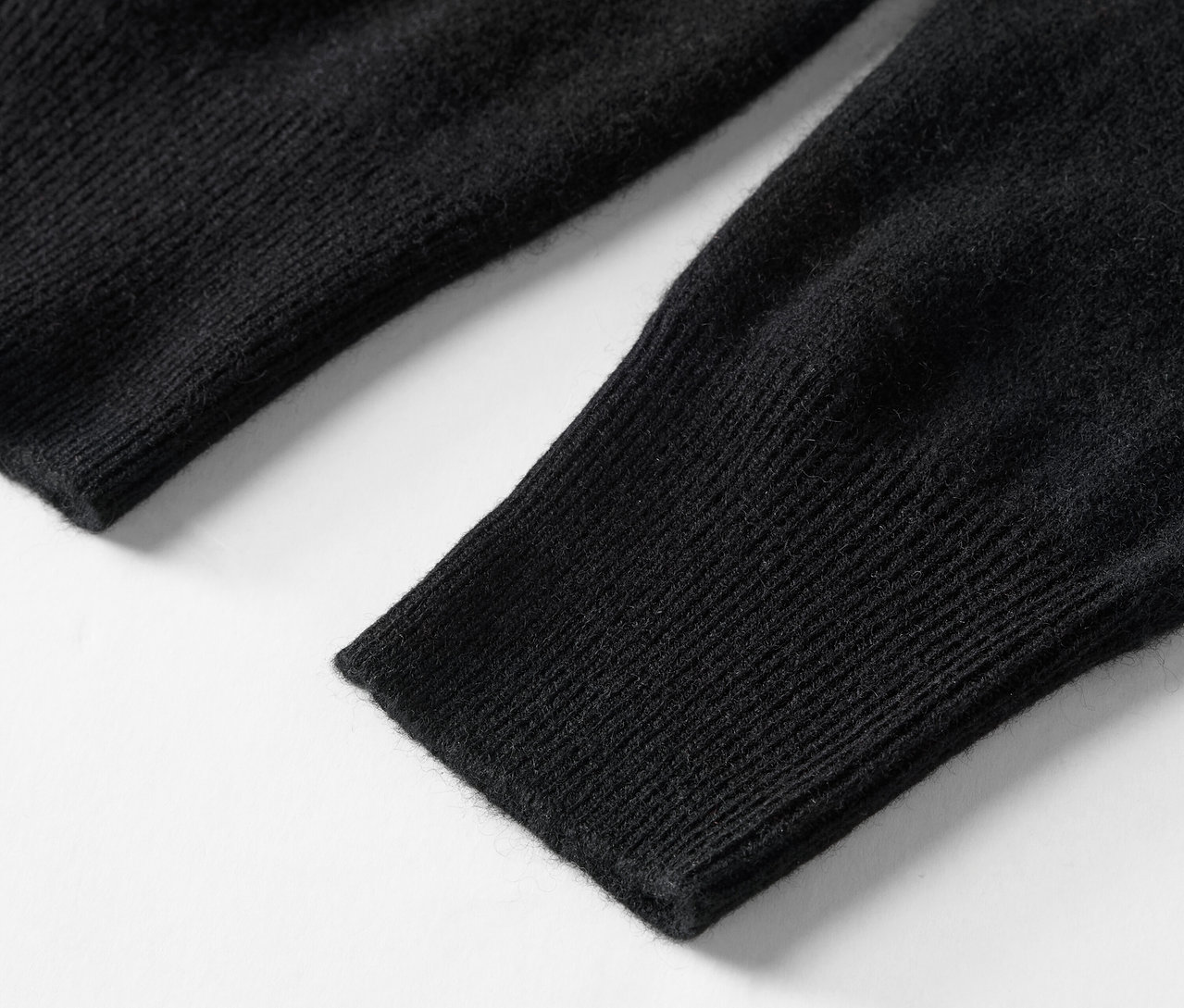 Zbliżenie na czarny, dziergany rękaw swetra.