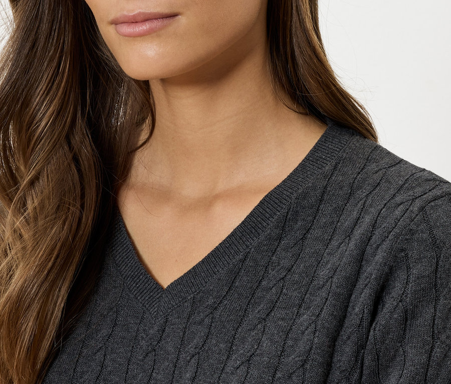 Zbliżenie kobiety w szarym swetrze z dekoltem w serek i warkoczowym splotem.