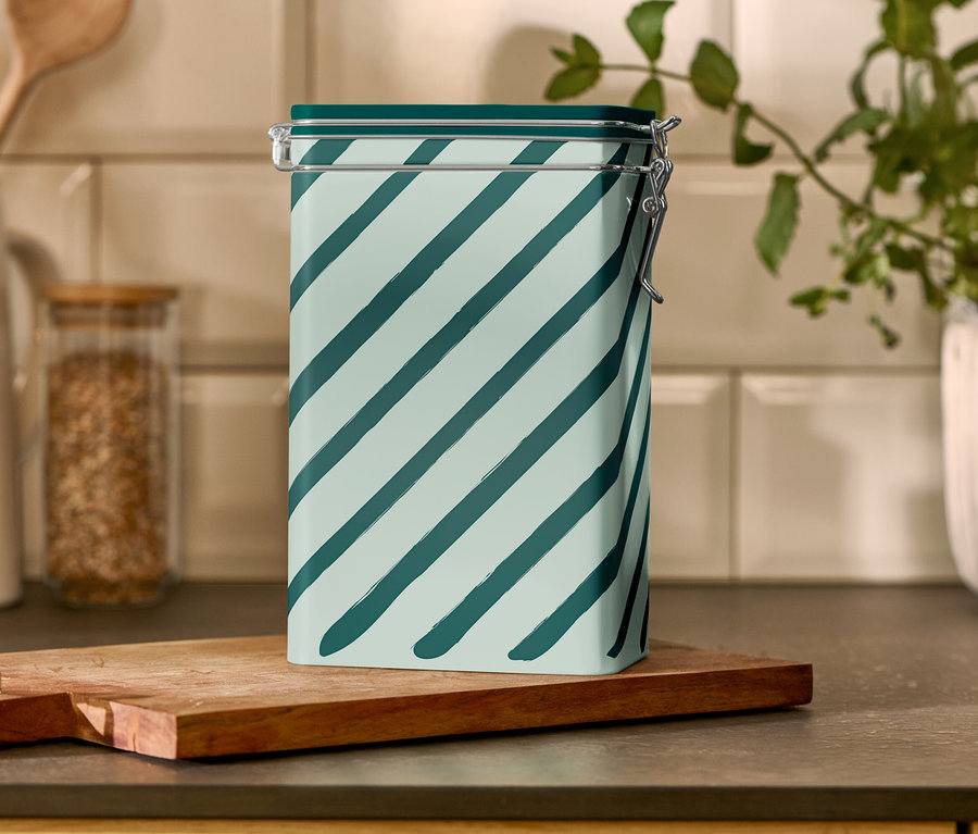 Puszka na kawę w paski stoi na drewnianej desce.