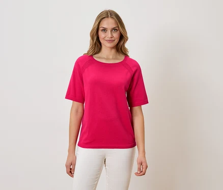 Kobieta ma na sobie różowy T-shirt i białe spodnie.