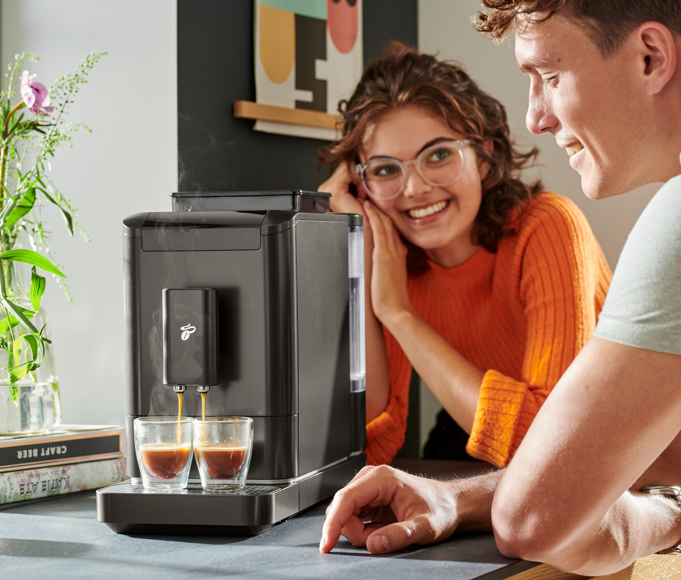 Dwie osoby obserwują, jak kawa spływa z automatycznego ekspresu do kawy »Esperto2 Caffè« do dwóch szklanek.