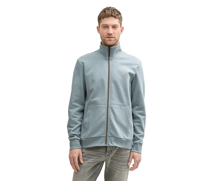 Mężczyzna ma na sobie bluzę dresową ze stójką Tom Tailor Grey Mint i szare dżinsy.