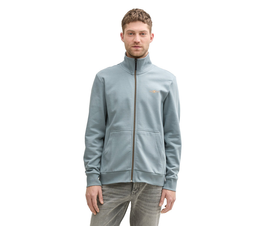Mężczyzna ma na sobie bluzę dresową ze stójką Tom Tailor Grey Mint i szare dżinsy.