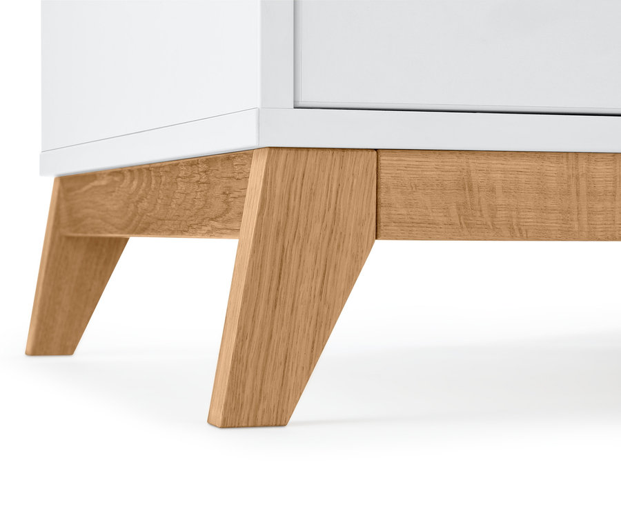 Szczegół białego kredensu z drewnianymi nogami.