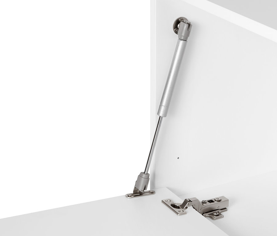 Detal białego modułu regału „Flemming” (ok. 75 x 37,5 cm) z klapą i srebrnym mechanizmem.