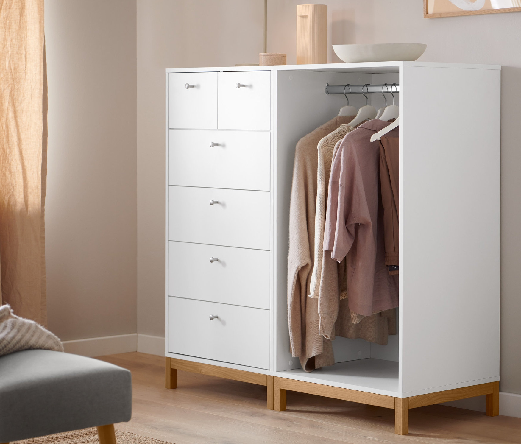 Szara ławka tapicerowana stoi obok białej komody.