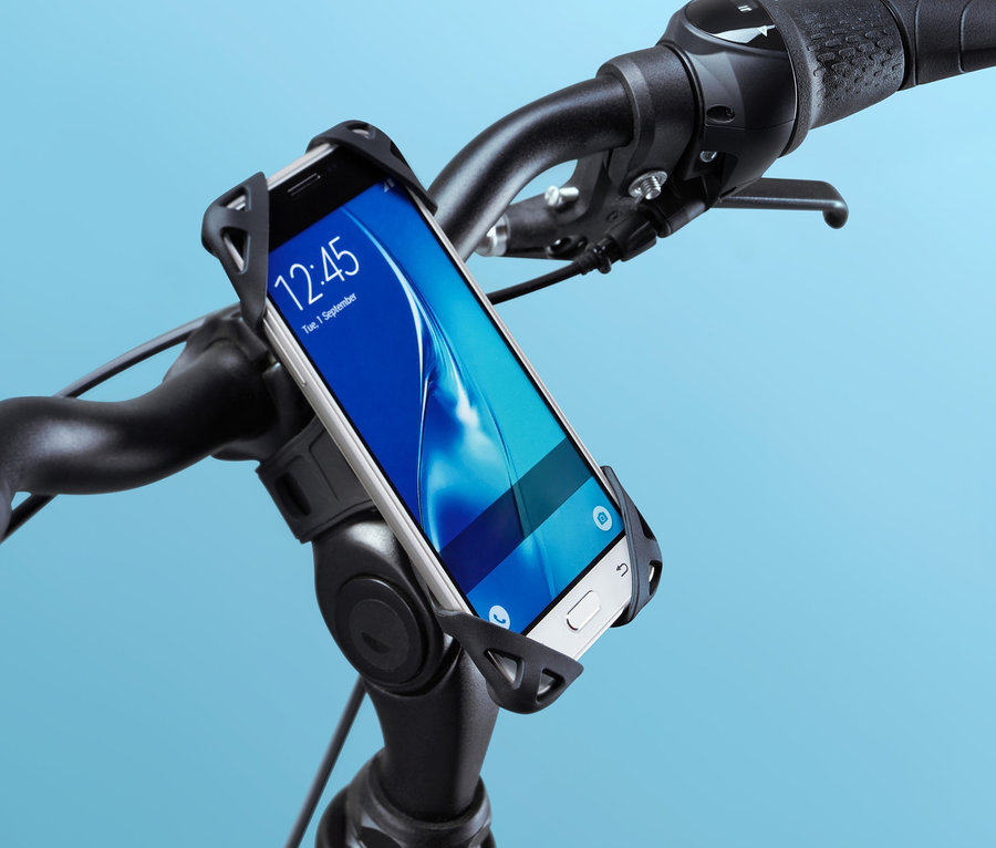 Zbliżenie na czarny rower z uchwytem rowerowym na smartfon na kierownicy, w którym znajduje się biały smartfon.
