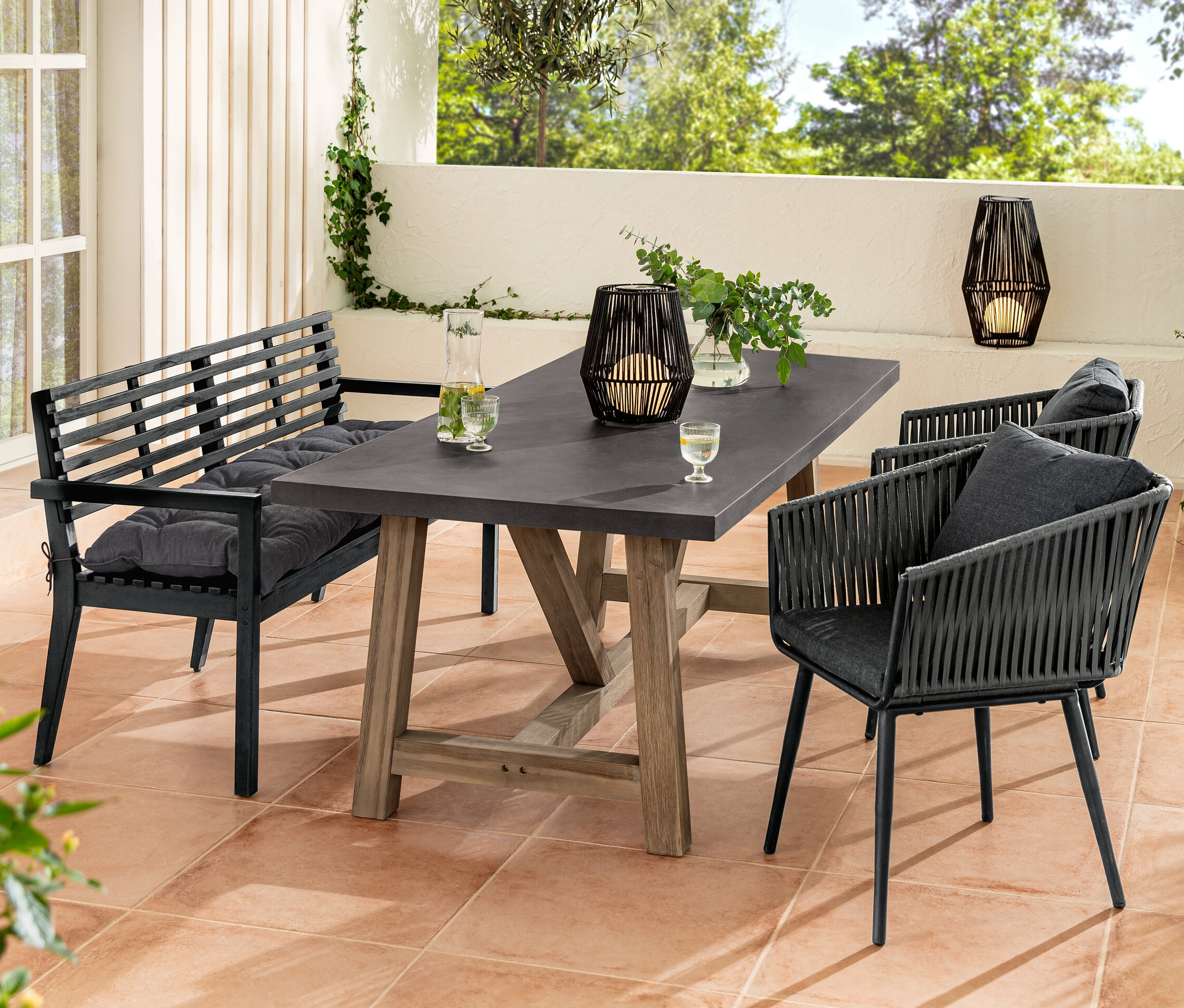 Zestaw mebli ogrodowych z ławką ogrodową z podłokietnikiem i poduszką Sun Garden, stołem z policementowym blatem, fotelem do jadalni z plecionką tekstylną i latarnią solarną.