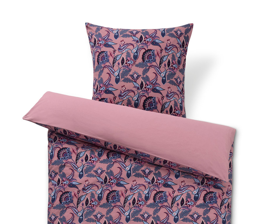 Różowa pościel z zimowego dżerseju w kwiatowy wzór i poduszka na górze.